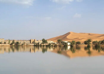 Sahara Desert Buildings along a lake filled by heavy rainfall in the desert town of Merzouga on O